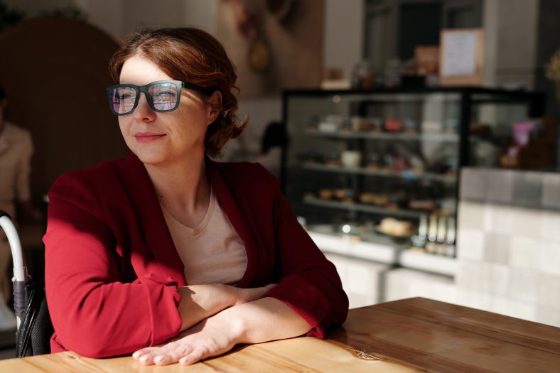 Woman in red long sleeve shirt wearing black framed eyeglasses